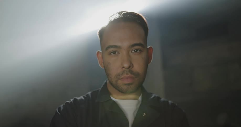 A man stands in a room with light coming in through a high window