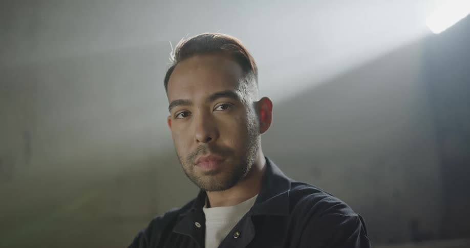 Car mechanic stands and looks at the camera at the garage