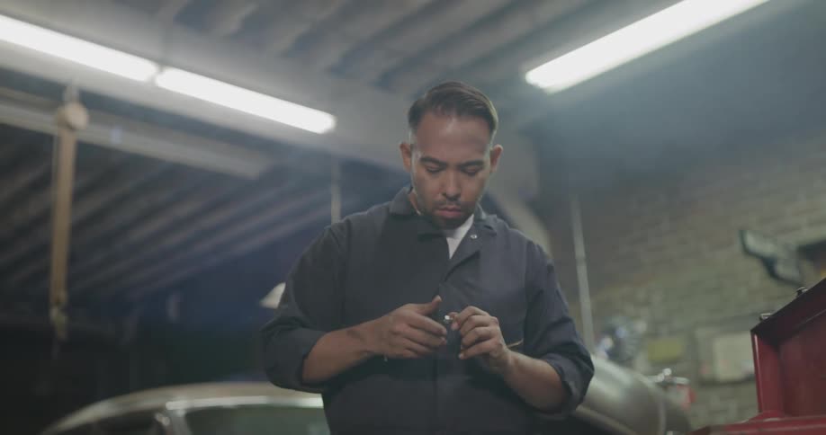 Mechanic contemplating which screw to use on a part at a body shop