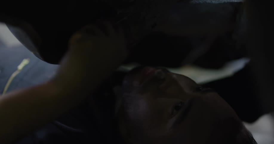 A mechanic works underneath a car