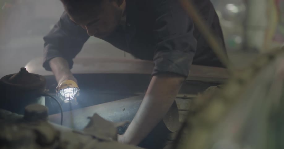 A mechanic works underneath the hood of a car