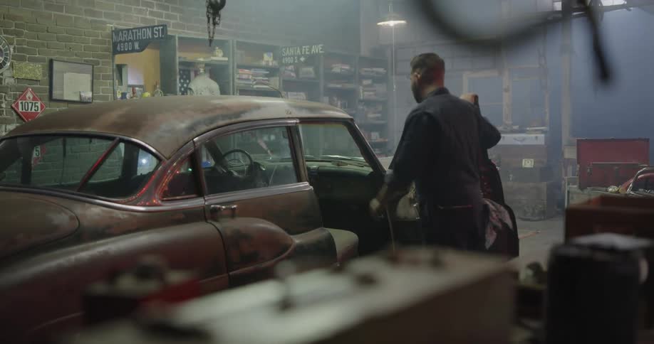 A mechanic opens the door of a vehicle hes working on in an auto shop