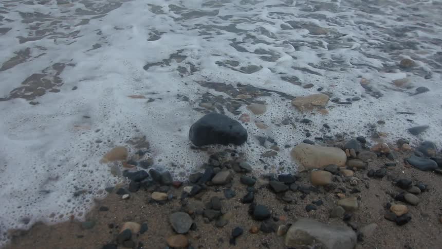 Water is crashing on the shore with many rocks