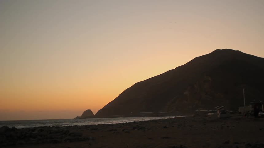 Looking down a beach and over the ocean at sunset