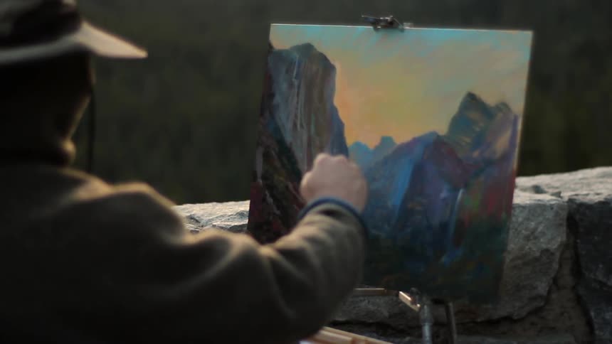 A man paints a landscape of the mountains