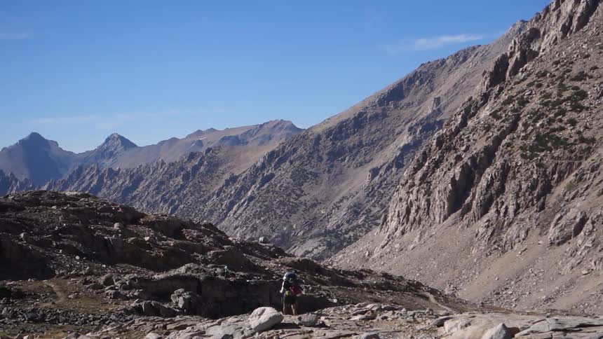 Hiker walks over rocks at the base of a mountain