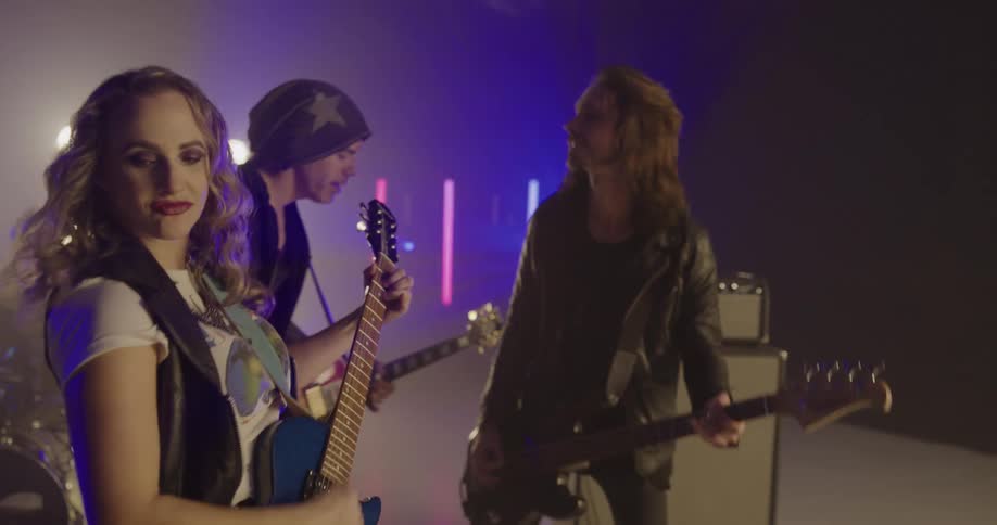 A band with three guitarists and a drummer perform on stage