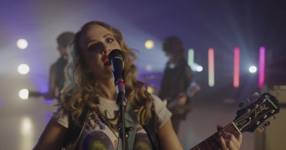 A female singer performs in front of a microphone while playing the guitar