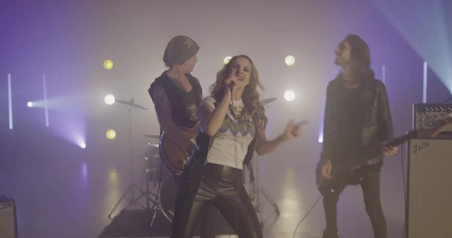 A band with a female singer performs on stage in front of flashing lights