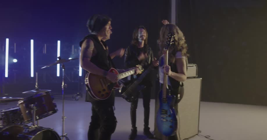 Female guitarists walks onto stage and greets other band members