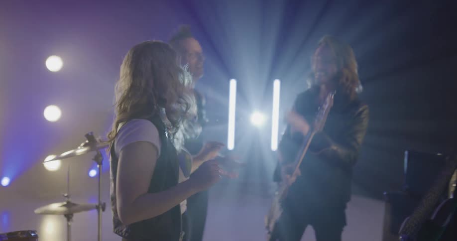 Rock band laughs jokes and talks on stage behind closed curtain
