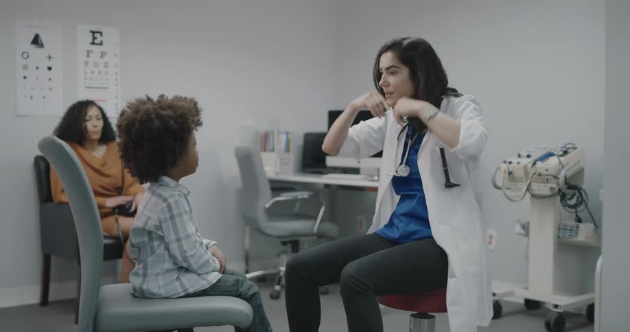 A female doctor examines a small boy patient while his mother watches