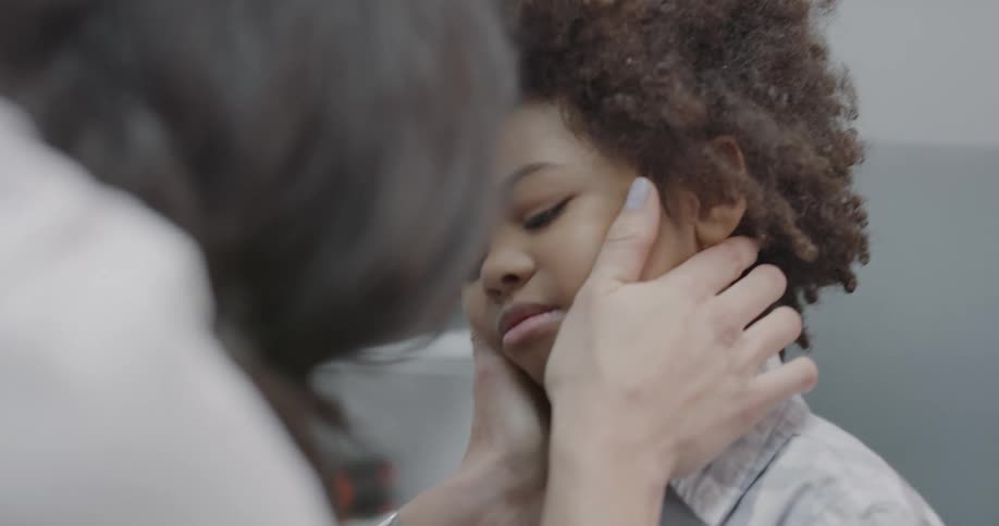 A woman holds the boys face