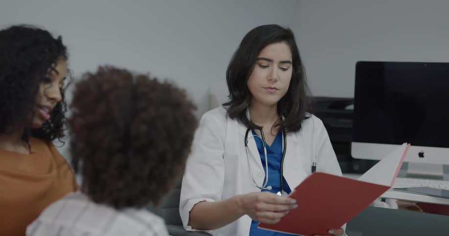 A nurse talks to a mother and her son as she holds a chart