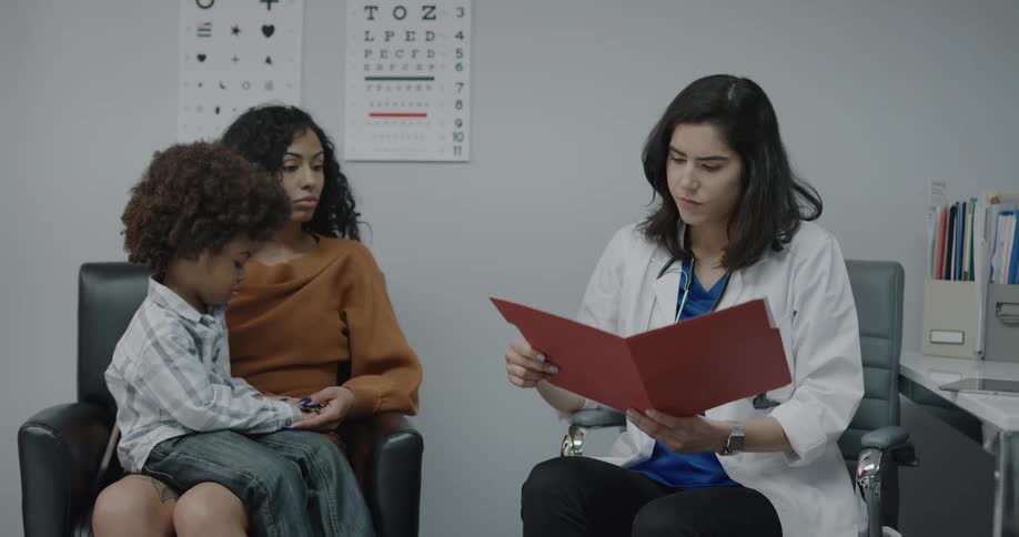 A doctor taking a folder from her desk and showing it to a mother and child