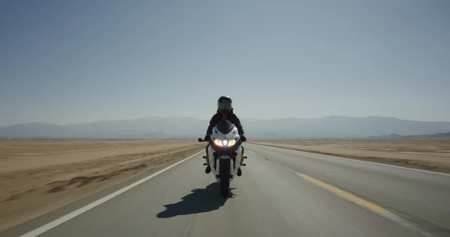A woman riding a motorcycle down a desert road