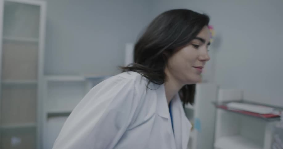 A nurse puts her lab coat on and walks out of the nurses office