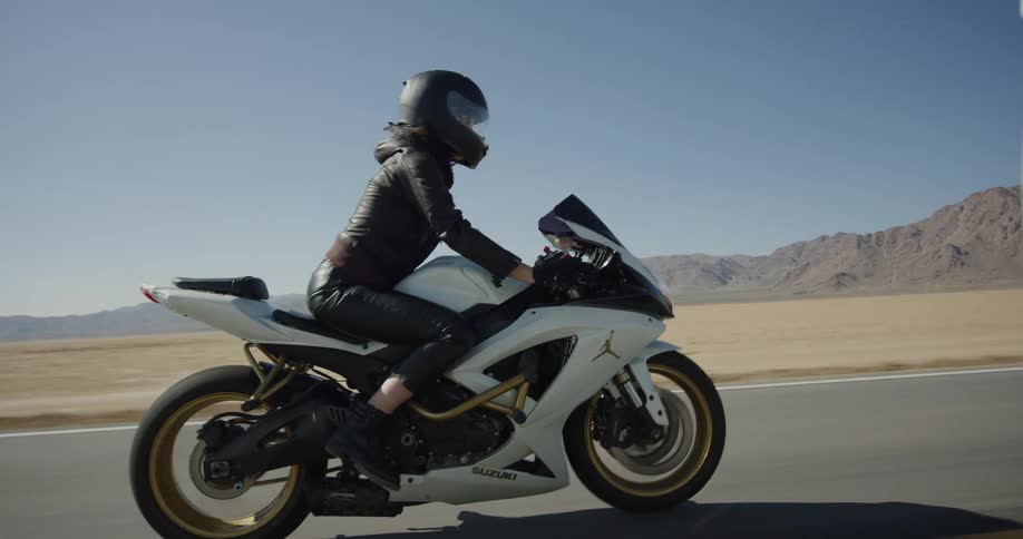 A woman riding a motorcycle on a desert road on a sunny day
