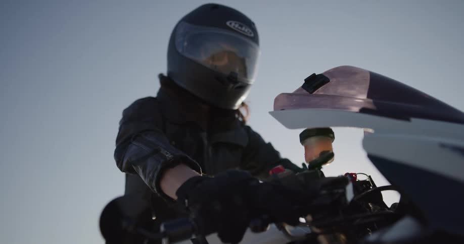 A woman checks the gears on her motorcycle before taking off in the desert