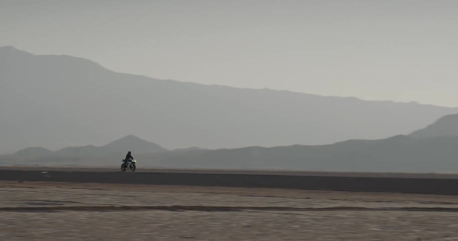 A woman drives a motorcycle down the street