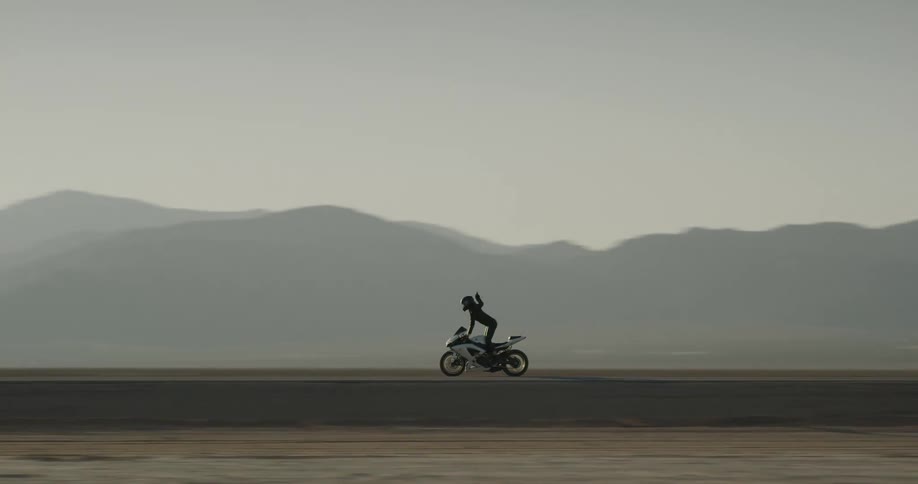 A motorcyclist stands up while riding through the desert