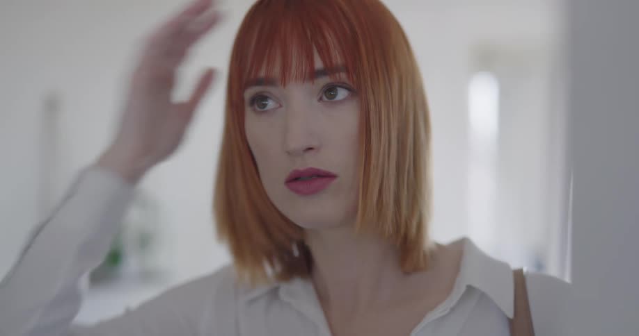 A woman fixes her hair and then walks away