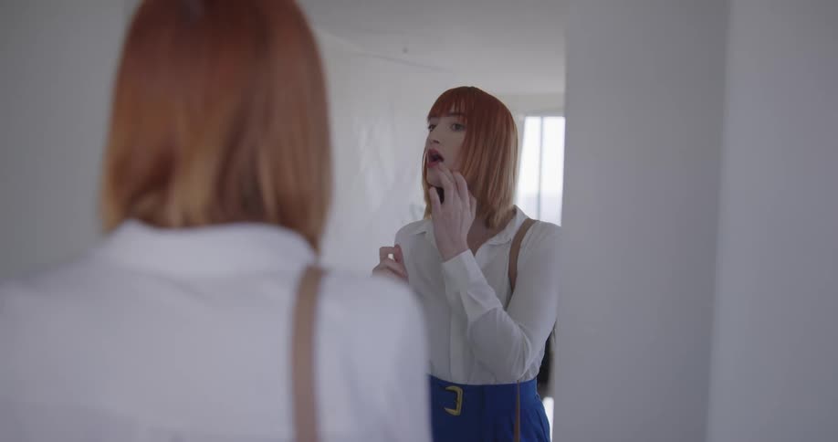 A woman stopping to adjust her appearance in a mirror before continuing onward