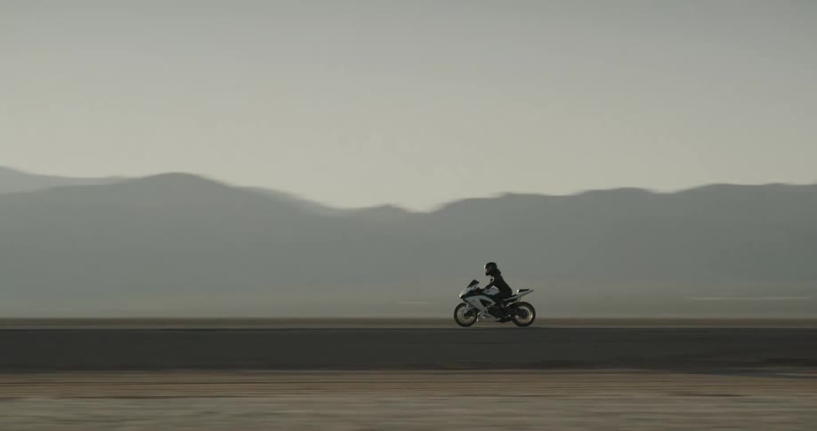 Female motorcyclist rides a motorcycle on a highway on the dry plains