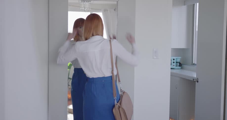Business woman checks herself in the mirror before leaving apartment