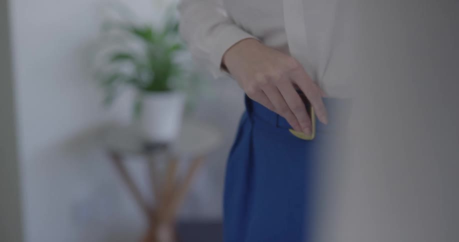 A woman adjusts her belt and hair in preparation for going out
