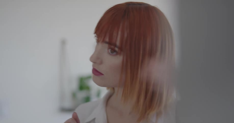 A woman perfects her hair by running her fingers through it