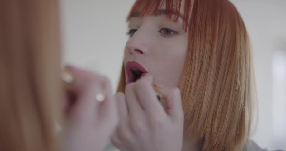 A woman applying lipstick in a mirror