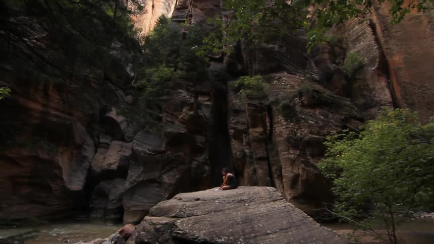 Someone sitting on a rock surrounded by tall cliffs