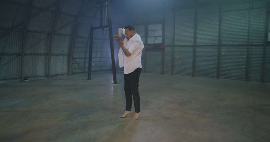 A man performs a modern dance in a large open hangar