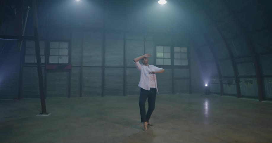An asian man performs a modern dance in a large open room with a domed ceiling