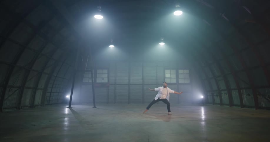 A man dancing in an empty hangar