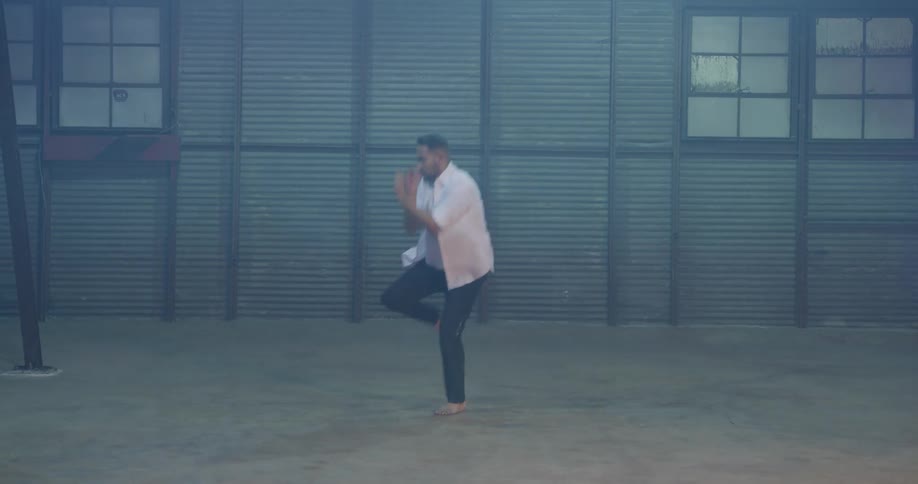 Man dances on barefoot on concrete floor in empty building