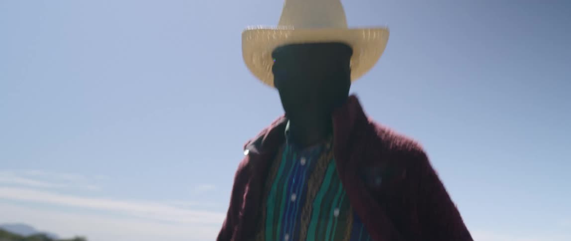 A man which all his skin covered in black fabric running down a dirt road towards the camera