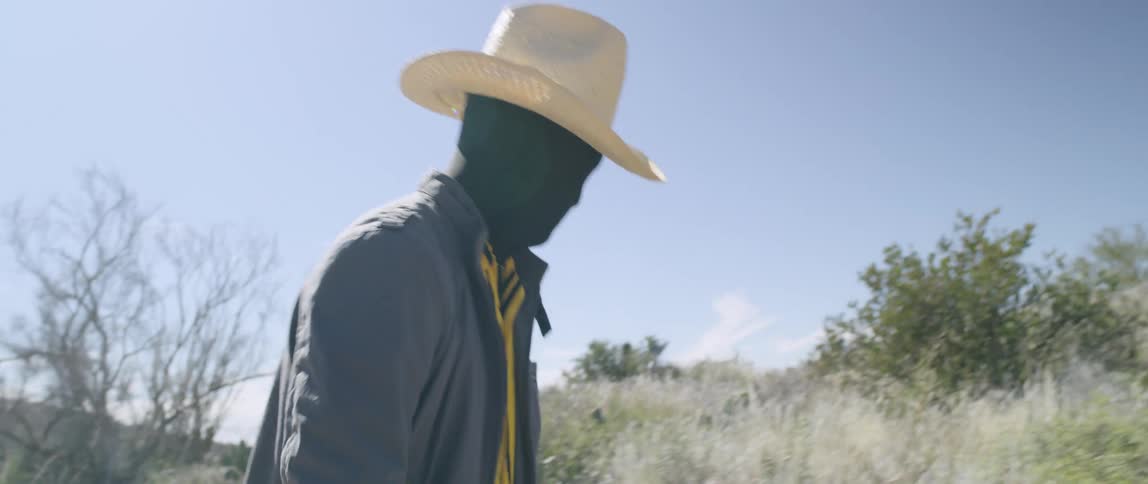 A man dressed as a scarecrow walks across the prairie