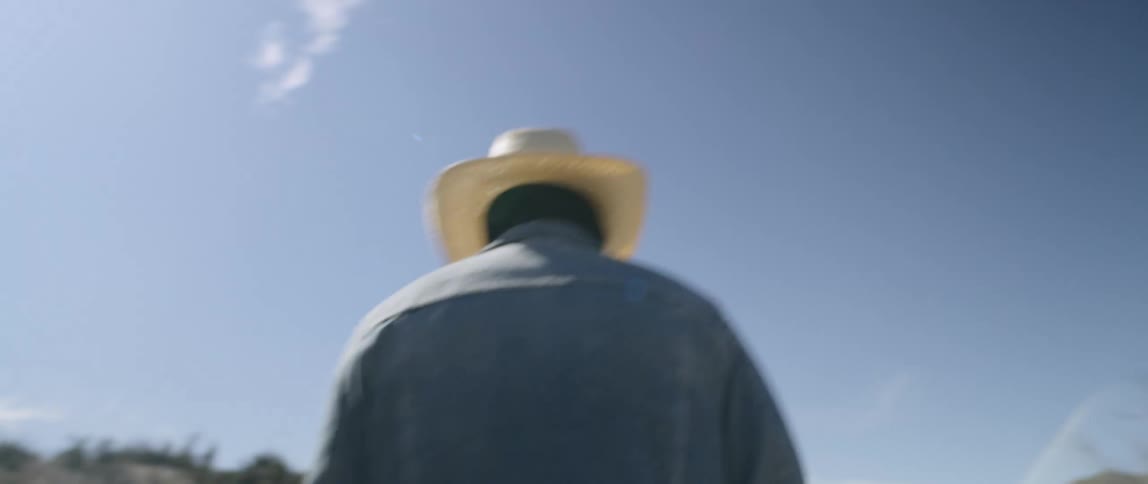A man dressed as a scarecrow walks across a field