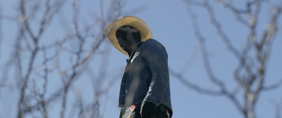 A man stands in the desert with his face covered in black fabric