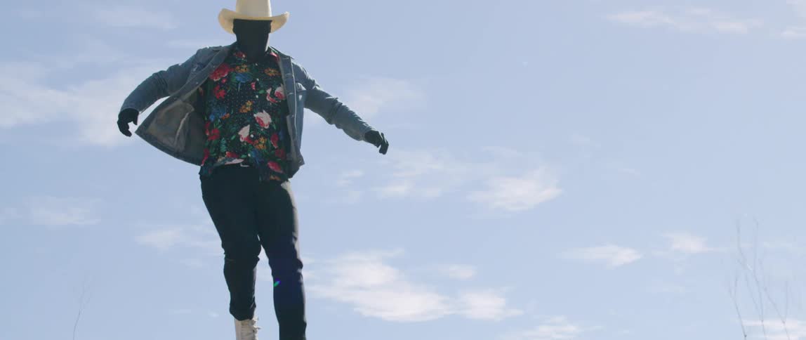 Cowboy wearing full head and face covering runs and jumps off cliff