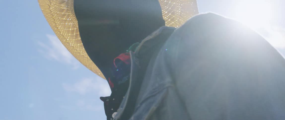 Man wearing black face mask and cowboy hat stands in the desert