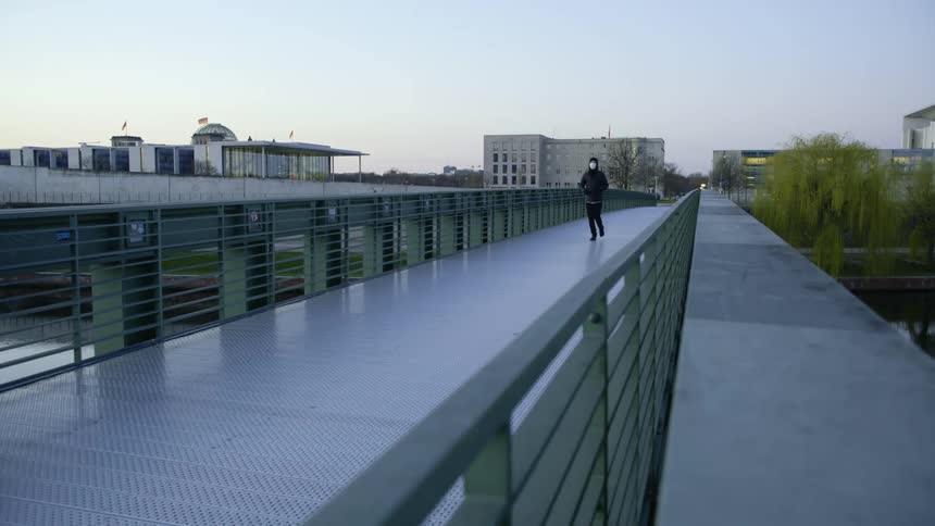 A man wearing a mask runs across a bridge
