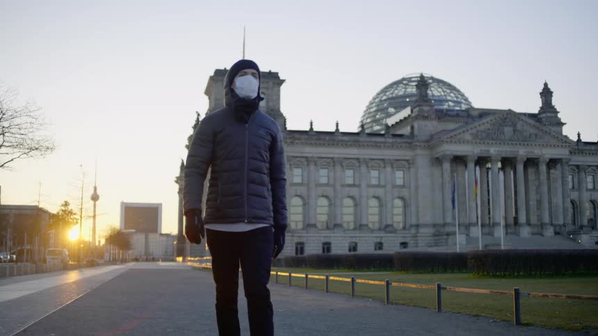 A person in a mask walks down a sidewalk