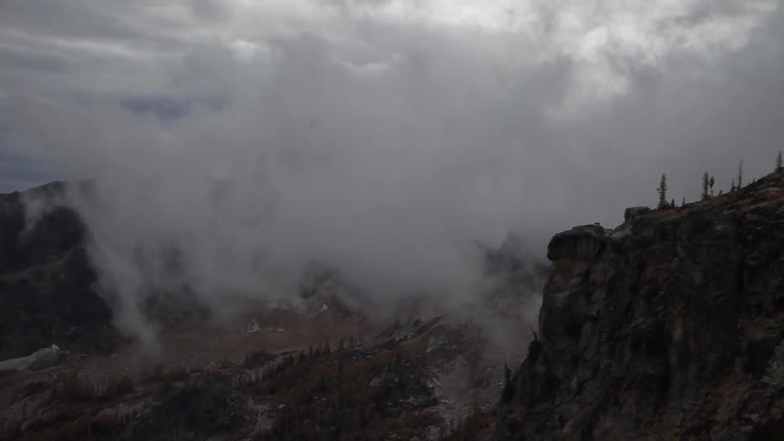 Low clouds move over mountains and cliffs on a stormy day