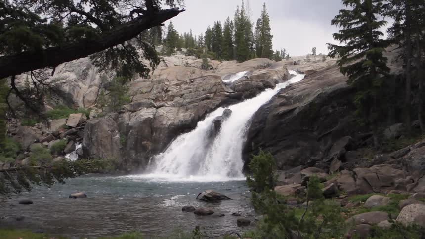 A fast flowing waterfall crashes into a pool