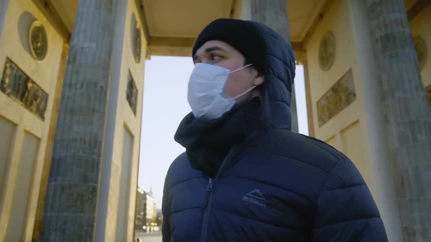 A man wearing a medical mask talks on a cell phone