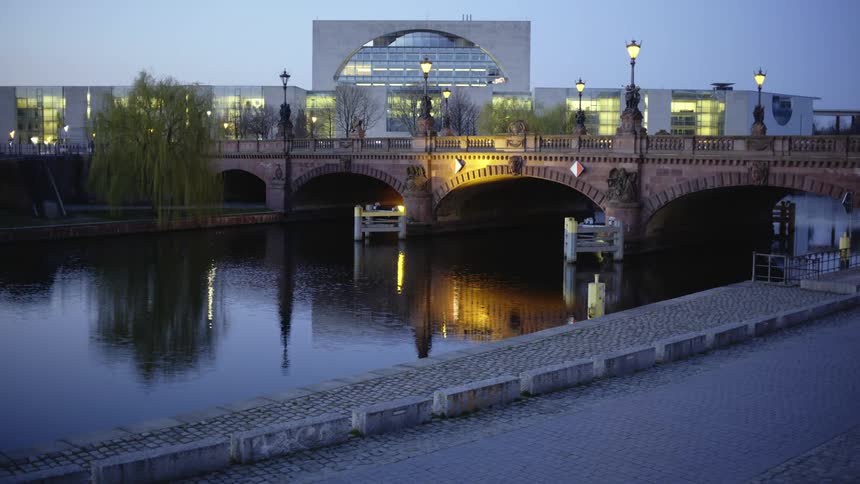 Bridge over waterway in front of large city building at night