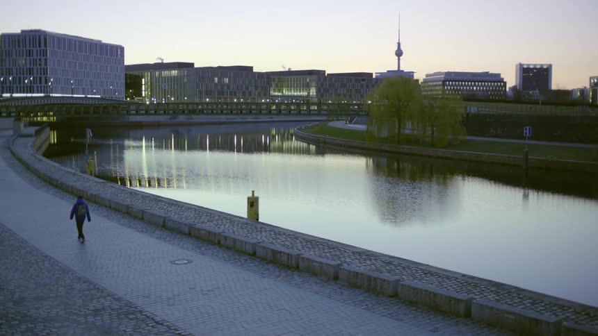 A man walks along the river bank